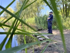 zdjęcie przedstawia policjantów przy brzegu stawu