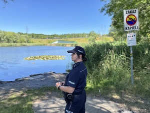 zdjęcie przedstawia policjantkę na tle wody i zarośli wokół stawu