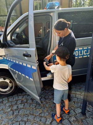 zdjęcie z wizyty w przedszkolu przedstawia policjantkę i przedszkolaka przy radiowozie
