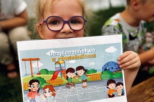 zdjęcie z wizyty w przedszkolu przedstawia przedszkolaka z plakatem dotyczącym bezpieczeństwa w wakacje