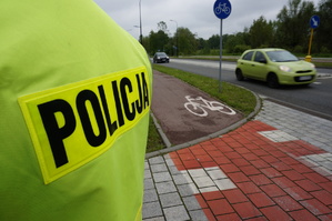 zdjęcie poglądowe - policjant stojący tyłem do drogi rowerowej - foto z archiwum rudzkiej policji