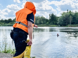zdjęcie przedstawia ćwiczenia z ratownictwa wodnego jak policjant ćwiczy rzuty w kierunku będącego w wodzie strażaka