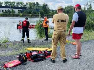 zdjęcie przedstawia ćwiczenia z ratownictwa wodnego gdy policjant i strażak ćwiczą, a przyglądają się temu prowadzący zajęcia