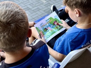 Dzieci oglądają planszę z grafikami dotyczącymi bezpieczeństwa w ruchu drogowym