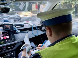 Policjant w radiowozie podczas sporządzania dokumentacji