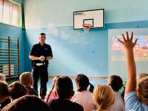 zdjęcie przedstawia wizytę policjanta w szkole na zajęciach z pierwszakami