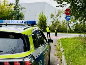 Na zdjęciu radiowóz a w tle policjanci
