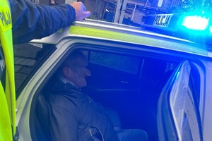 zdjęcie przedstawia zatrzymanego kierowcę siedzącego na tylnym fotelu policyjnego radiowozu