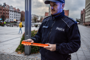 zdjęcie policjanta trzymającego odblaskową opaskę