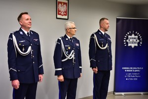 zdjęcie przedstawia salę w której odbywa się uroczysta zbiórka, na fotografii widać Komendanta Wojewódzkiego Policji i dwóch zmieniających się komendantów
