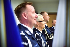 zdjęcie przedstawia salę w której odbywa się uroczysta zbiórka, na fotografii widać Komendanta Wojewódzkiego Policji i dwóch zmieniających się komendantów