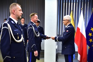 zdjęcie przedstawia salę w której odbywa się uroczysta zbiórka, na fotografii widać Komendanta Wojewódzkiego Policji składającemu gratulacje i nominacje odchodzącemu komendantowi