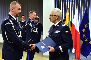 zdjęcie przedstawia salę w której odbywa się uroczysta zbiórka, na fotografii widać Komendanta Wojewódzkiego Policji składającemu gratulacje nowemu komendantowi