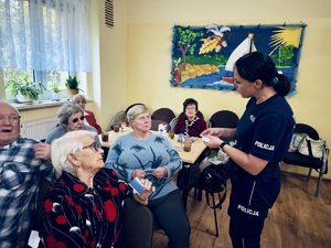 Na zdjęciu policjantka wręcza karty seniorom