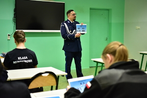 zdjęcie przedstawia klasę z uczniami oraz policjanta prowadzącego zajęcia