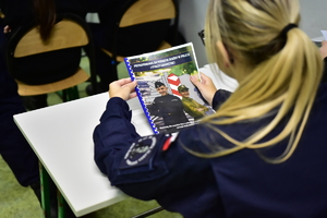 zdjęcie przestawia uczennicę klasy mundurowej trzymającą skrypt pomocny w nauce