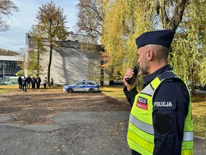 zdjęcie przedstawia policjanta kierującego ewakuacją na placu przy komisariacie