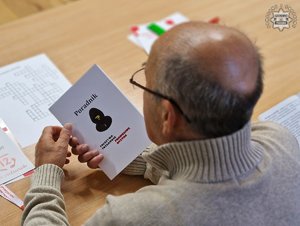 zdjęcie przedstawia seniora z ulotką dotyczącą oszustw