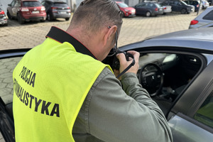 zdjęcie przedstawia policyjnego technika fotografującego samochód którym poruszali się sprawcy