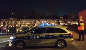 zdjęcie policyjnego radiowozu na tle cmentarza