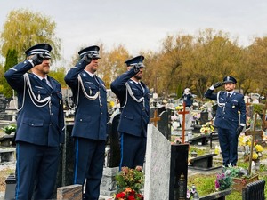 zdjęcie przedstawia policjantów na cmentarzu stojących i salutujących przed grobem zmarłego kolegi