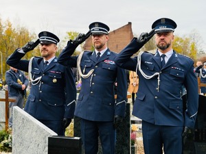 zdjęcie przedstawia policjantów na cmentarzu oddających hołd zmarłemu koledze
