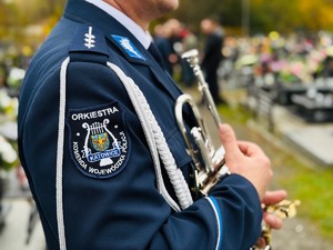 zdjęcie przedstawia policjanta z orkiestry reprezentacyjnej na cmentarzu