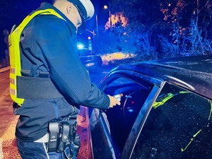 zdjęcie przedstawia policjanta z drogówki podczas nocnej kontroli trzeźwości kierowcy samochodu osobowego