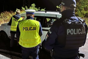zdjęcie przedstawia policjantów w trakcie kontroli samochodu