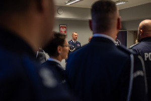 zdjęcie przedstawia miejsce uroczystej zbiórki w trakcie której policjanci słuchają komendanta