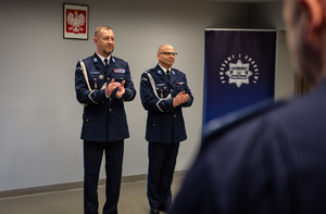 zdjęcie przedstawia miejsce uroczystej zbiórki w trakcie której komendant i jego zastępca biją brawa dla wyróżnionych policjantów