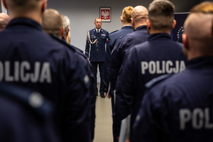 zdjęcie przedstawia miejsce uroczystej zbiórki w trakcie której widać stojących w rzędach policjantów i komendanta w trakcie przemówienia