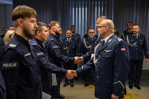 zdjęcie przedstawia miejsce uroczystej zbiórki w trakcie której komendant i jego zastępca gratulują wyróżnionym policjantom