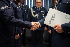 zdjęcie przedstawia miejsce uroczystej zbiórki w trakcie której komendant przekazuje gratulacje policjantowi