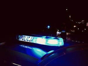 zdjęcie przedstawia dach policyjnego radiowozu z włączonymi światłami niebieskimi