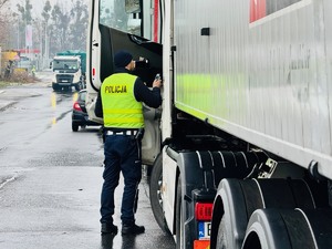 zdjęcie przedstawia policjanta ruchu drogowego w trakcie kontroli kierowcy samochodu ciężarowego zaparkowanego w miejscu objętym zakazem zatrzymywania się