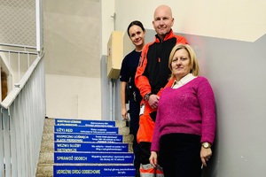 Osoby pozują do zdjęcia na oklejonych schodach w budynku