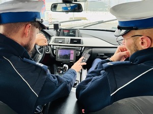zdjęcie przedstawia policjantów z drogówki w radiowozie wyposażonym w wideorejestrator gdy przeglądają naganie z przekroczenia prędkości