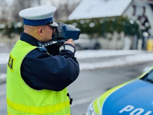 zdjęcie przedstawia policjanta z drogówki w trakcie pomiaru prędkości