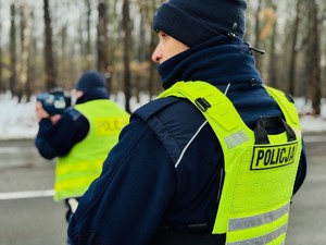 zdjęcie przedstawia policjantów z drogówki w trakcie pomiaru prędkości