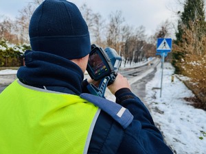 zdjęcie przedstawia policjanta z drogówki z radarem mierzącego prędkość