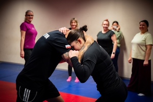 zdjęcie z zajęć na sali ćwiczeń rudzkiej komendy, widoczni na nich instruktor i uczestniczące kobiety