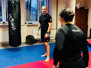 zdjęcie z zajęć na sali ćwiczeń rudzkiej komendy, widoczni na nich instruktor i uczestniczące kobiety