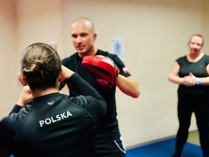 zdjęcie z zajęć na sali ćwiczeń rudzkiej komendy, widoczni na nich instruktor i uczestniczące kobiety