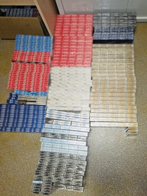 zdjęcie przedstawia przechwycone paczki papierosów ułożone na podłodze policyjnego biura