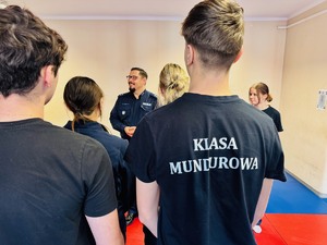 zdjęcie przedstawia uczniów klasy mundurowej na sali gimnastycznej przed zajęciami