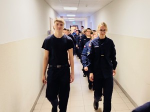 zdjęcie przedstawia uczniów klasy mundurowej maszerujących korytarzem komendy