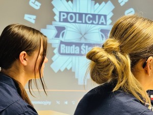 zdjęcie przedstawia uczniów klasy mundurowej i logo policji wyświetlane na ścianie