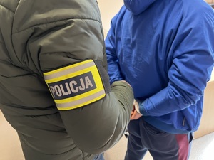 zdjęcie poglądowe pokazujące jak policjant kryminalny prowadzi zatrzymanego