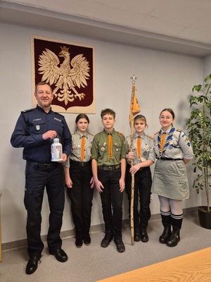 zdjęcie przedstawia harcerzy przekazujących komendantowi Betlejemskie Światełko Pokoju w gabinecie szefa rudzkiej Policji